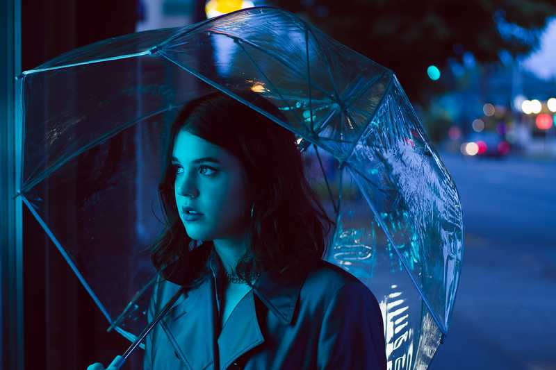 Model holding an umbrella with moody blue lighting
