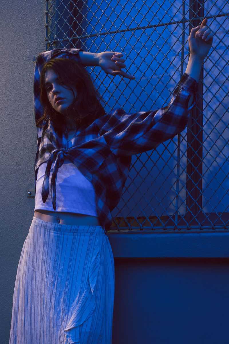 Model posing by a building with moody blue lighting