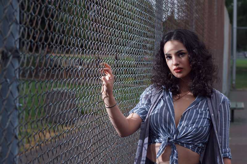 Model posing next to a chain link fence